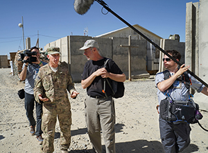 U.S. Army Chaplain (Major General) Father Paul K. Hurley talks to CHAPLAINS producer/director Martin Doblmeier with cameraman Nathan DeWild and sound technician Jeremy Zunk in Afghanistan, June 2014.