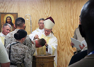 The Most Reverend Timothy P. Broglio, Archbishop for the Military Services, USA, baptizes a U.S. Marine at Camp Leatherneck in Afghanistan in 2014.